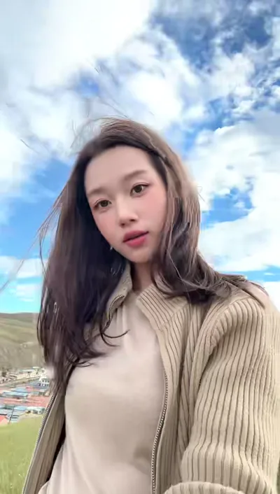 马丽娟近景，身后是蓝天与草地